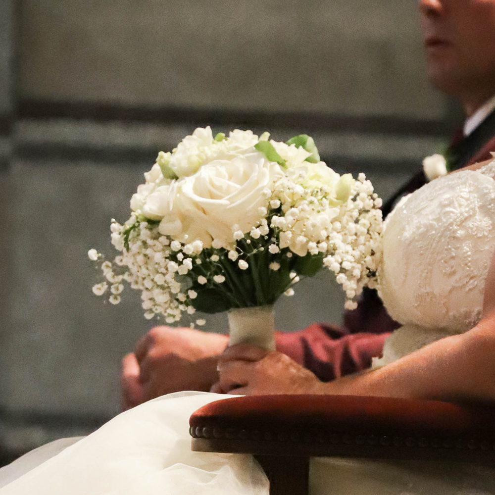 Mariée tenant un bouquet blanc de roses et gypsophile